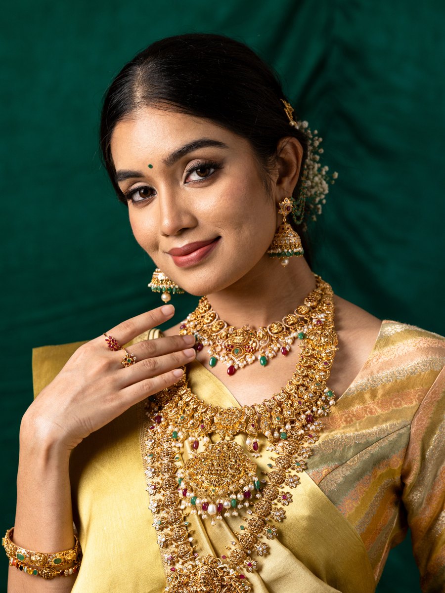 Model wearing a Shree Omkar temple gold bridal necklace set with rubies and emeralds